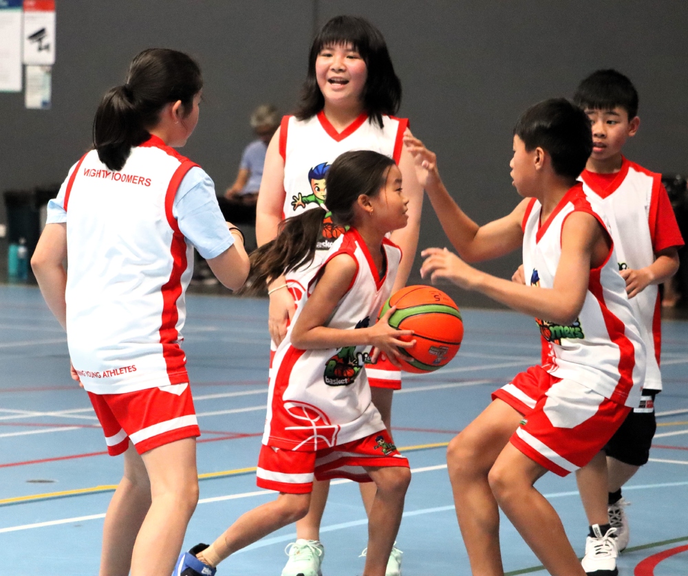 A group of children actively playing basketball on an outdoor court, showcasing teamwork and enthusiasm.